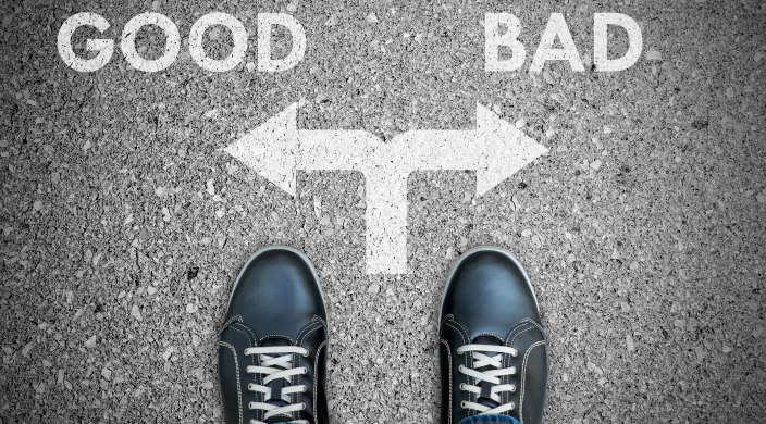 A pair of feet faced with a choice: do good or do bad, which are noted on the ground in front of the feet