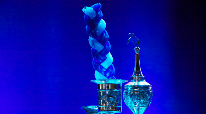Havdallah candle and silver spice set against a blue lit background