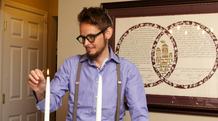 Person dressed up at home while lighting Shabbat candles in a living room setting