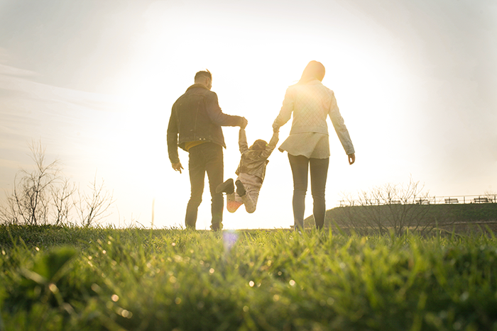 an image of two parents swinginga child by the arms; imageis a little blurry
